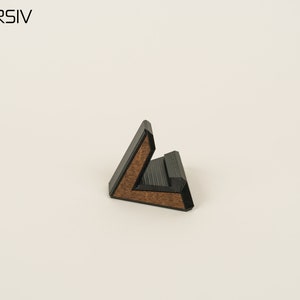 May include: A black and brown wooden phone stand shaped like a triangle.