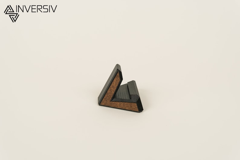 May include: A black and brown wooden phone stand shaped like a triangle.