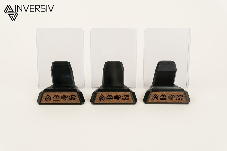 May include: Three black acrylic card display stands with clear acrylic panels. Each stand has a wooden base with a laser-engraved design of four elements: fire, earth, air, and water.