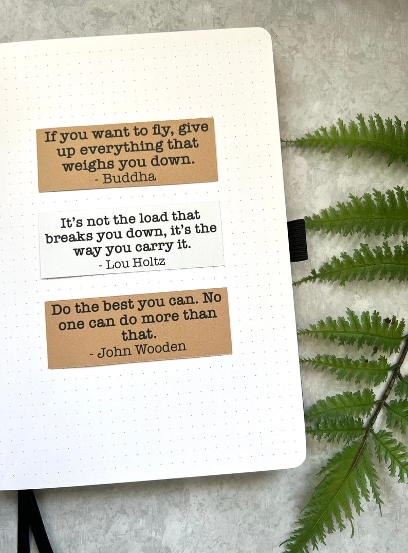 Quotes by various authors in Kraft brown and white sticker paper strips on an A5 dotted journal.