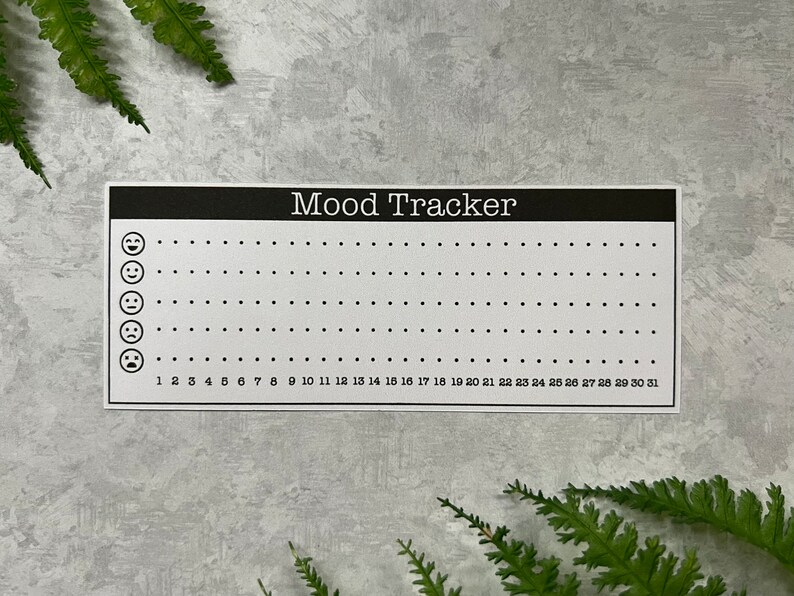One white mood graph habit tracker stickers on a light gray background with two green fern leaves.