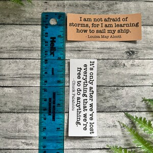 Book quotes in Kraft brown and white sticker paper strips next to a blue ruler that shows they are 1.20 in.(H) X 3.25 in. (W)