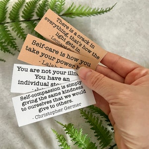 mental health quotes in brown and white sticker paper strips being held by hand to show scale.