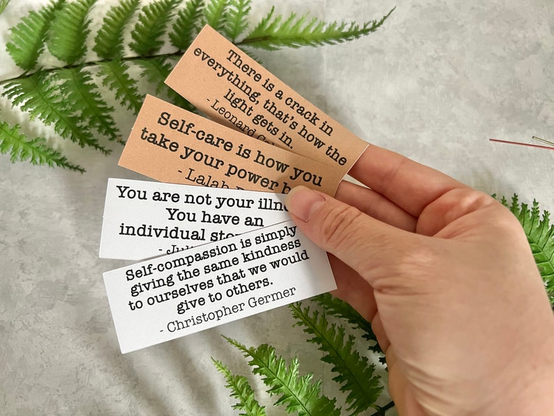 mental health quotes in brown and white sticker paper strips being held by hand to show scale.