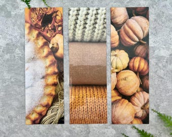 Puede incluir: Tres marcapáginas rectangulares con imágenes estacionales. El de la izquierda muestra un pastel con azúcar glas y calabazas. El centro presenta tejidos de punto apilados en crema, beige y amarillo mostaza. La derecha muestra varias calabazas.