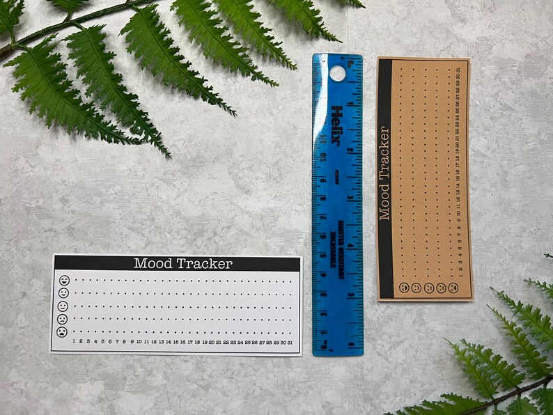 One brown and one white Mood graph habit tracker sticker shown against a blue six-inch ruler to show the diameter measurement of 2.00 in.(H) X 5 in. (W)