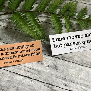 Book quotes by Alice Walker and Paulo Coelho in Kraft brown and white sticker paper strips Slanted on a green fern leaf.