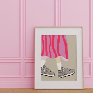 May include: A framed illustration of a person's legs wearing a pink and red striped skirt and gray sneakers. The background is a light brown color.