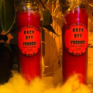 Pode incluir: Duas velas vermelhas em forma de pilar com o texto "BACK OFF VOODOO!" em um rótulo vermelho. Os rótulos também incluem "Return To Sender Candle" e "72hr Burn Time". As velas são embaladas em plástico transparente.