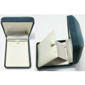 May include: A blue velvet jewelry box with a white interior and a hinged lid. The box is designed to hold a necklace or other jewelry.