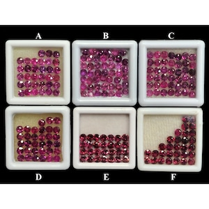 May include: Six white square trays filled with small, round, faceted gemstones in shades of pink and red. The gemstones are arranged in varying quantities within each tray, showcasing their colour and cut.