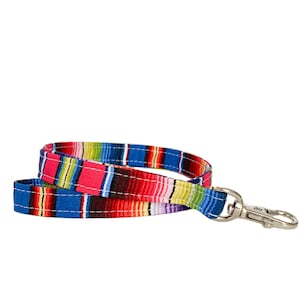 May include: A colorful lanyard with a striped pattern in shades of blue, red, pink, green, and yellow. The lanyard has a silver-colored metal swivel clasp. The fabric is stitched with white thread.