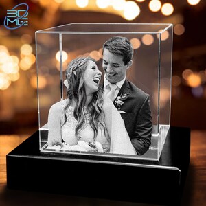 May include: A black and white photo of a couple, a bride and groom, smiling and laughing together. The photo is encased in a clear crystal cube on a black base.