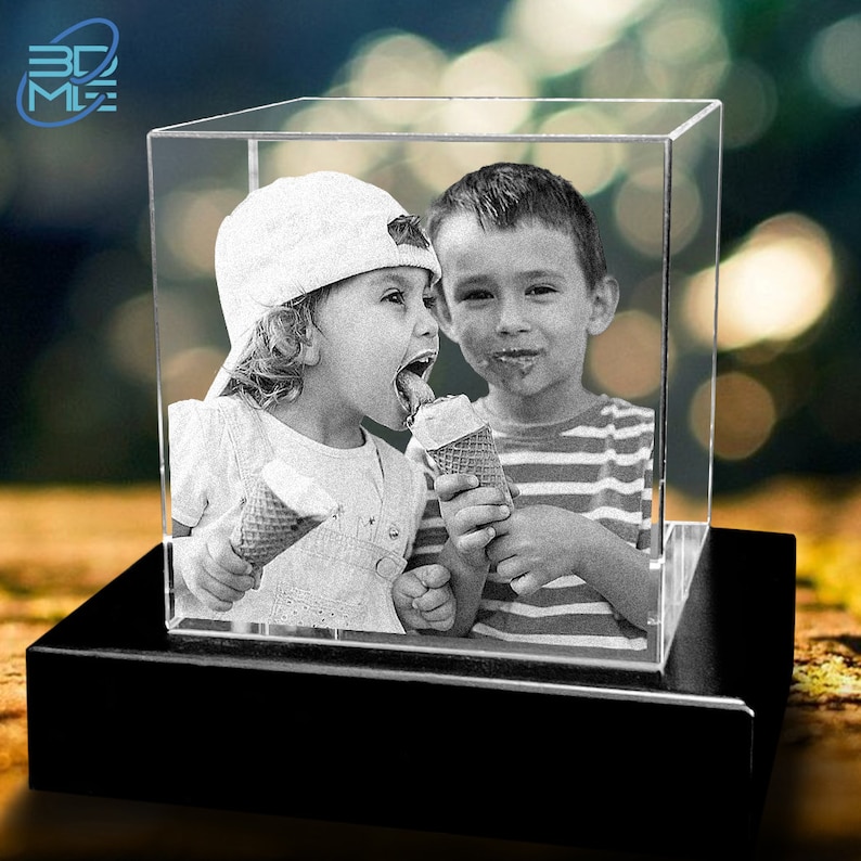 May include: A black and white photo of two children eating ice cream cones, encased in a clear glass cube on a black base.