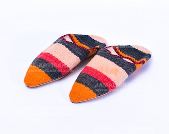 May include: A pair of colorful striped slippers with a pointed toe. The slippers are made of woven fabric in shades of orange, red, pink, black, and gray.
