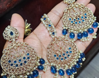 May include: A pair of gold earrings with blue and clear stones, and a matching gold necklace with blue and clear stones.