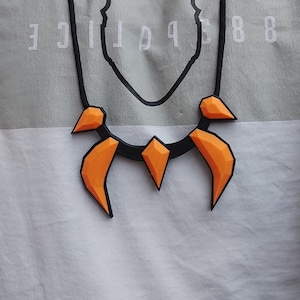 May include: A black necklace with orange claw-like pendants. The necklace is worn by a person wearing a white shirt with the word "POLICE" printed on it.