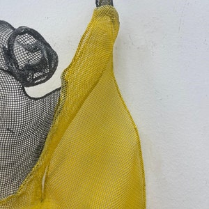 May include: A yellow and black wire mesh sculpture with a flowing, organic shape.