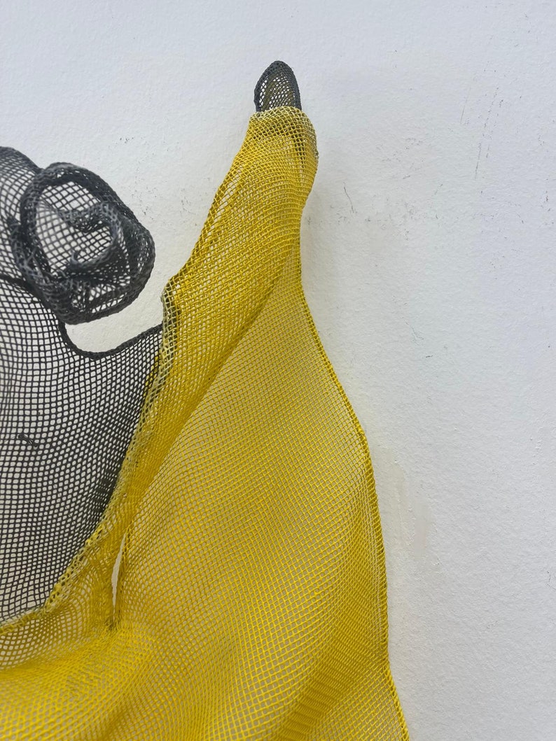 May include: A yellow and black wire mesh sculpture with a flowing, organic shape.