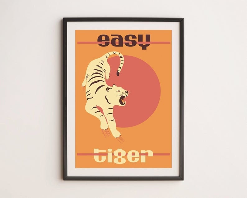 May include: A retro-style poster with a white tiger leaping in front of a red sun. The text "easy tiger" is printed in black letters.