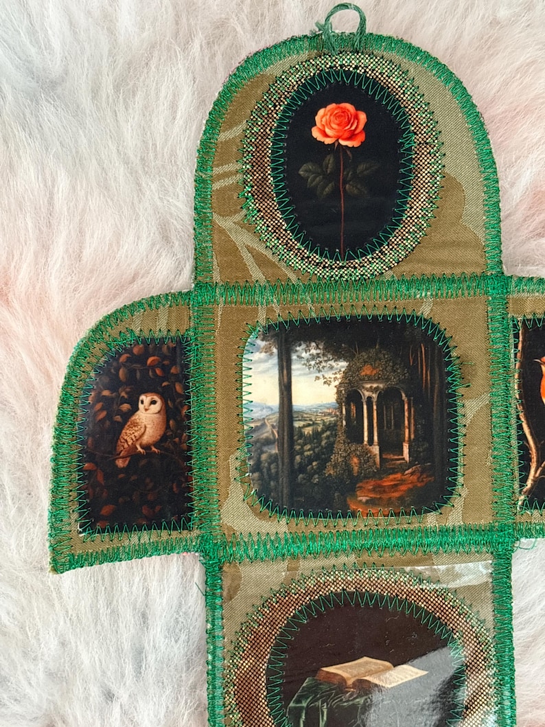 K&ouml;nnte beinhalten: Ein handgefertigtes Stoffkunstwerk mit mehreren Paneelen, die jeweils ovale und rechteckige Rahmen haben. Die Rahmen zeigen Bilder einer Rose, einer Eule und einer Landschaft. Die Paneele sind mit gr&uuml;nen F&auml;den zusammengen&auml;ht.