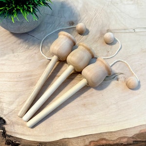 May include: Three wooden cup and ball toys with string and wooden balls. The toys are made of natural wood and have a light brown color.