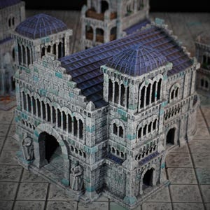 May include: A detailed model of a stone building with a blue roof and arched windows. The building has a large arched entrance and is made of grey and white stone with blue accents.