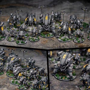 Puede incluir: Una colección de 15 robots en miniatura pintados en negro, gris y amarillo. Los robots tienen varios diseños y poses, algunos están de pie, algunos caminan y algunos disparan armas. Los robots están dispuestos sobre una superficie gris.