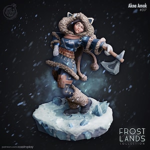 May include: A detailed figurine of Akna Amak from the Frost Lands Collection. The figure wears a blue coat with fur trim, a fur-lined hood, and holds a small axe. The figure stands on a snowy base. The text "Akna Amak #317" is visible.