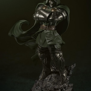 May include: A detailed, green and silver statue of Doctor Doom, a Marvel Comics supervillain, standing on a rocky base. He is wearing a green cape and a metal mask.