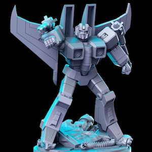 Puede incluir: Una figura de acción de plástico gris de un robot con alas, de pie sobre una base. El robot tiene una pistola en una mano y está en posición de combate.