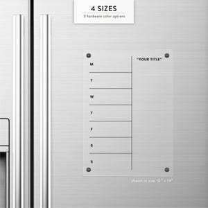 May include: A clear acrylic weekly planner with the text "YOUR TITLE" and days of the week. The planner is shown in a 10" x 14" size and has 4 sizes and 3 hardware color options.