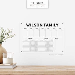 May include: A clear acrylic family chore chart with the text "WILSON FAMILY" at the top. The chart includes sections for each day of the week, plus spaces for chores, and notes. The size shown is 28"x20".