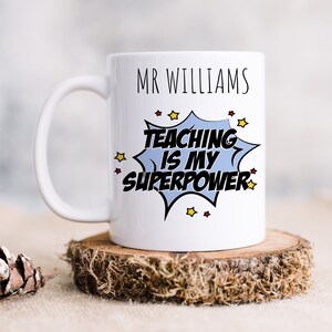May include: White ceramic mug with a blue and black comic book style speech bubble that says "Teaching is my superpower". The mug also has the name "Mr. Williams" printed on it.