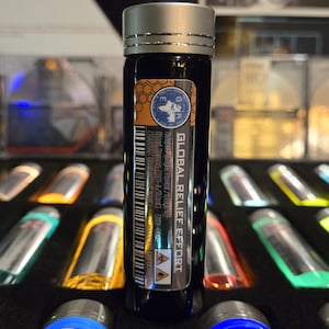 May include: A cylindrical glass vial with a silver screw-top lid, featuring a label that reads Global Relief Effort, Subject: Night Hunter/Stage 4, Blood Sample-001-A/50ml, and includes a barcode, hazard symbols, and a circular logo with a map.