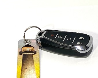 May include: A silver keychain with a lighthouse image and a black car key fob.