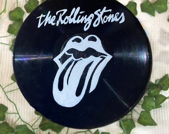 May include: A black vinyl record with the Rolling Stones logo painted in white. The logo is a tongue sticking out with a red mouth and a white outline.