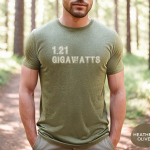 May include: A green t-shirt with the text "1.21 GIGAWATTS" printed on the front. The shirt is made of a soft, comfortable material and is available in a heather olive color.