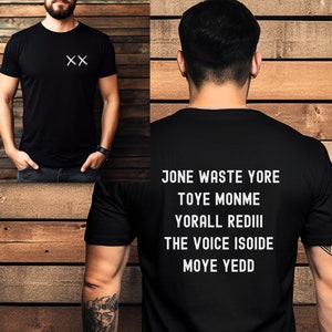 May include: Black t-shirt with white text on the back that reads "Jone Waste Yore Toye Monme Yorall Rediii The Voice Isoide Moye Yedd". The front of the shirt has two white "X" marks.