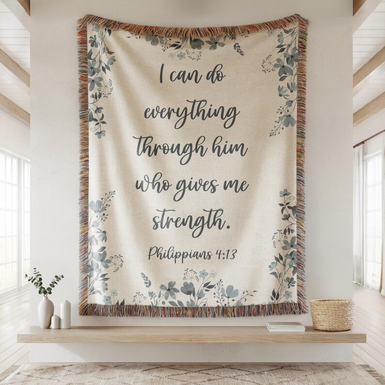 May include: Cream-colored woven throw blanket with the text "I can do everything through him who gives me strength. Philippians 4:13." The blanket has a floral border in shades of blue and a fringed edge.