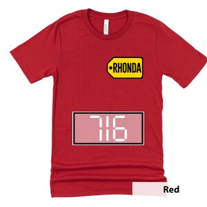Puede incluir: Camiseta roja con una etiqueta amarilla que dice "RHONDA" y un rect&aacute;ngulo rosa con n&uacute;meros blancos que dicen "716".