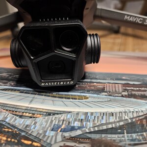 May include: A black drone with the text "MAVIC 3 PRO" on the arm. The drone has a camera with a Hasselblad logo on the front.