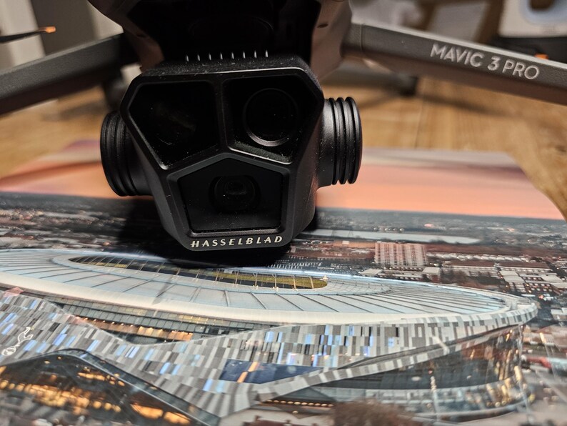 May include: A black drone with the text "MAVIC 3 PRO" on the arm. The drone has a camera with a Hasselblad logo on the front.