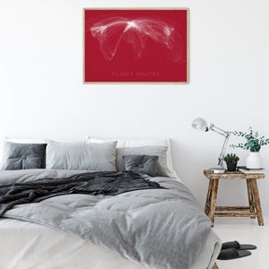 May include: A framed print of a world map with white lines representing flight routes on a red background. The text "FLIGHT ROUTES" is printed at the bottom of the map.