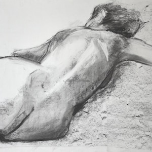 May include: A charcoal drawing of a figure lying down, viewed from the back. The figure's form is rendered with varying shades of gray, creating depth and highlighting the contours of the body. The artwork has a classic, artistic feel.