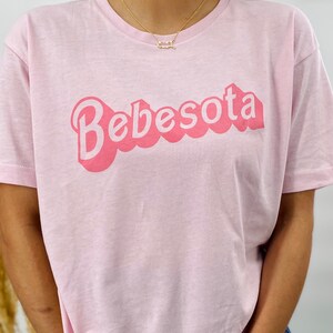 May include: Pink t-shirt with the text "Bebesoita" in a retro bubble font.