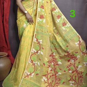May include: A yellow saree with a floral pattern in red, green, and white. The saree has a thin border with a repeating pattern.