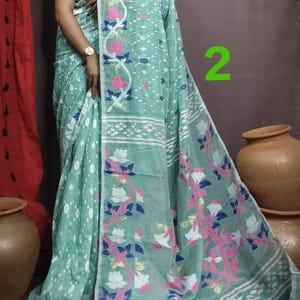 May include: A light blue and white saree with a floral pattern. The saree has a white border with a pink and blue floral design. The saree is draped over a woman's body.