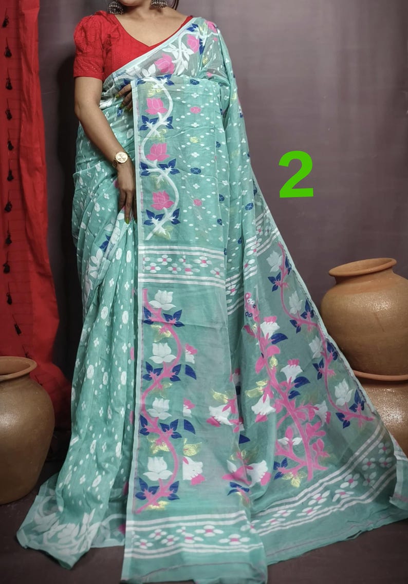 May include: A light blue and white saree with a floral pattern. The saree has a white border with a pink and blue floral design. The saree is draped over a woman's body.