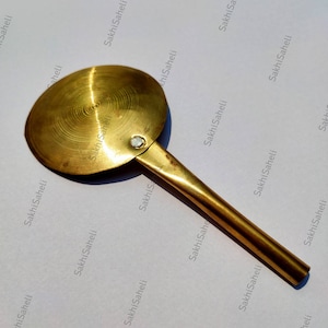 Peut inclure: Une louche en laiton avec un bol rond et un long manche. La louche a un aspect usé et vieilli.